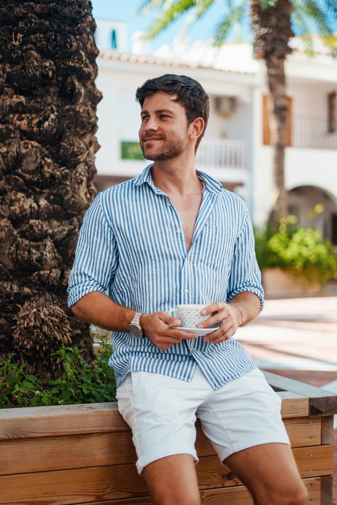 Homem usando camisa listrada e short claro.
